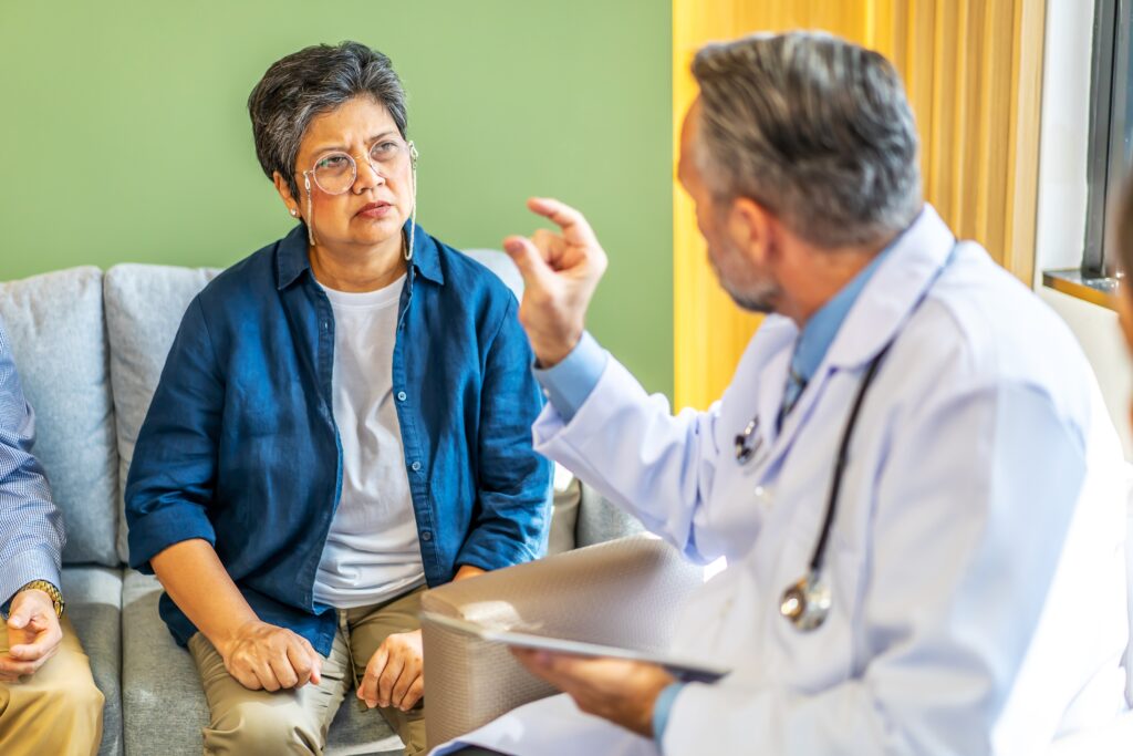 Dokter die uitlegt aan een patiënt die geboeid luistert